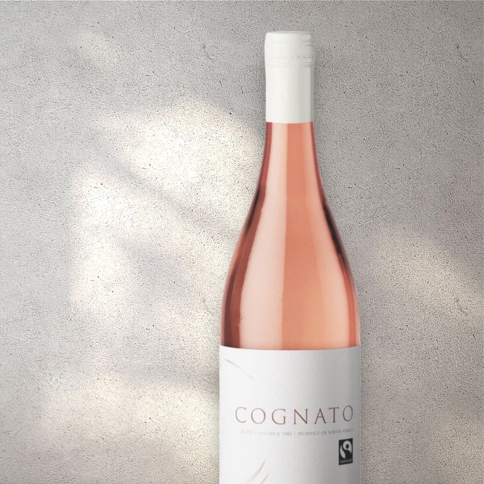 Closeup of a Cognato Pinotage Cinsault alcohol-free rosé wine bottle with a detailed label, set against a textured concrete wall, highlighting its refined design and blush pink colour.