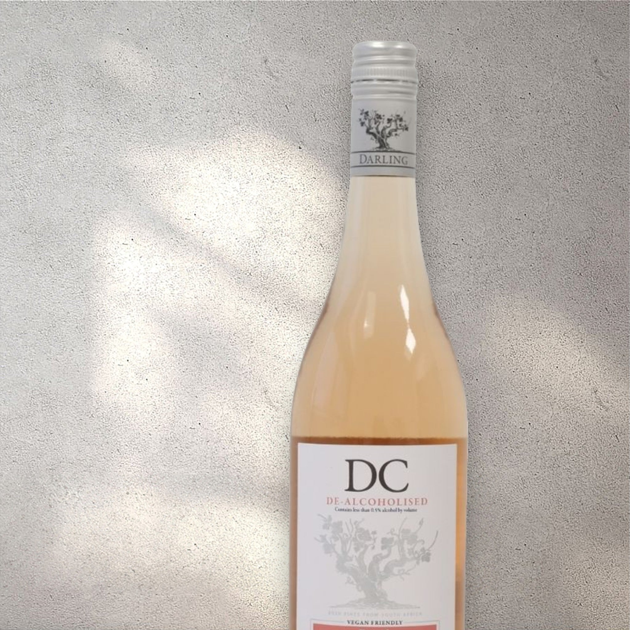 Closeup of a Darling Cellars Sauvignon Blanc alcohol-free rosé wine bottle with a detailed label, set against a textured concrete wall, highlighting its refined design and soft pink colour.