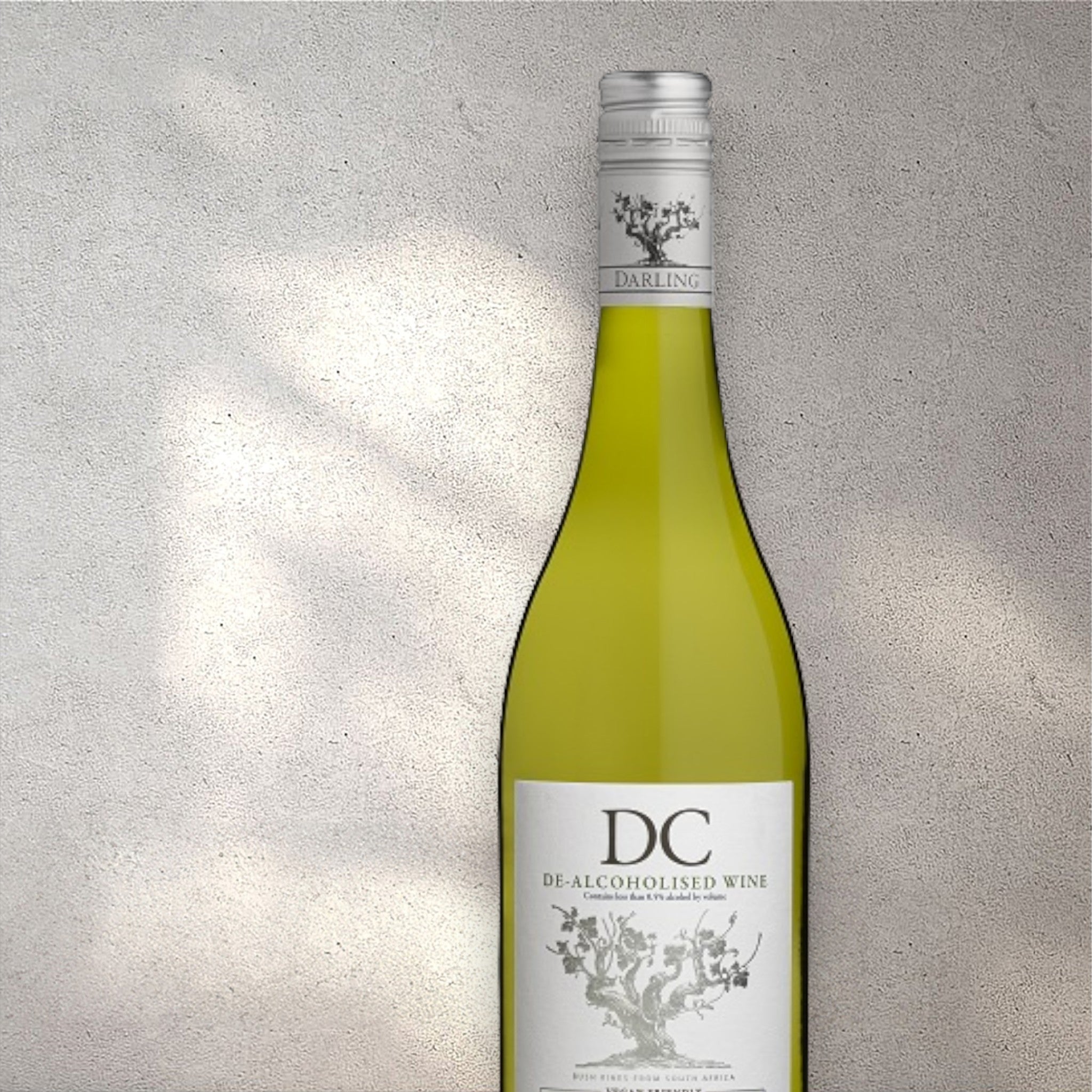 Closeup of a Darling Cellars alcohol-free white wine bottle with a detailed label, set against a textured concrete wall, highlighting its refined design and light yellow colour.