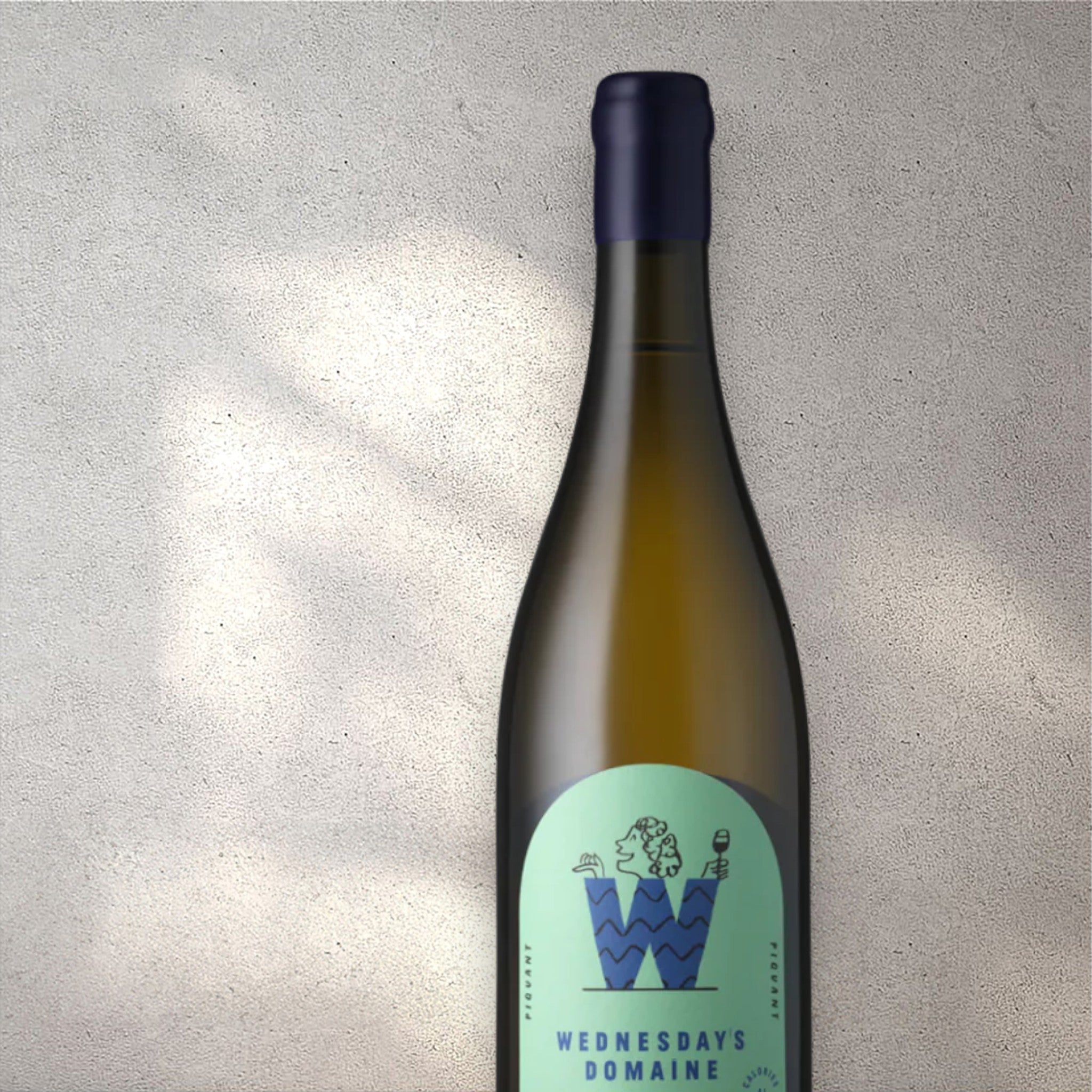 Closeup of a Wednesday’s Domaine Piquant alcohol-free white wine bottle with a detailed label, set against a textured concrete wall, highlighting its refined design and light yellow color.