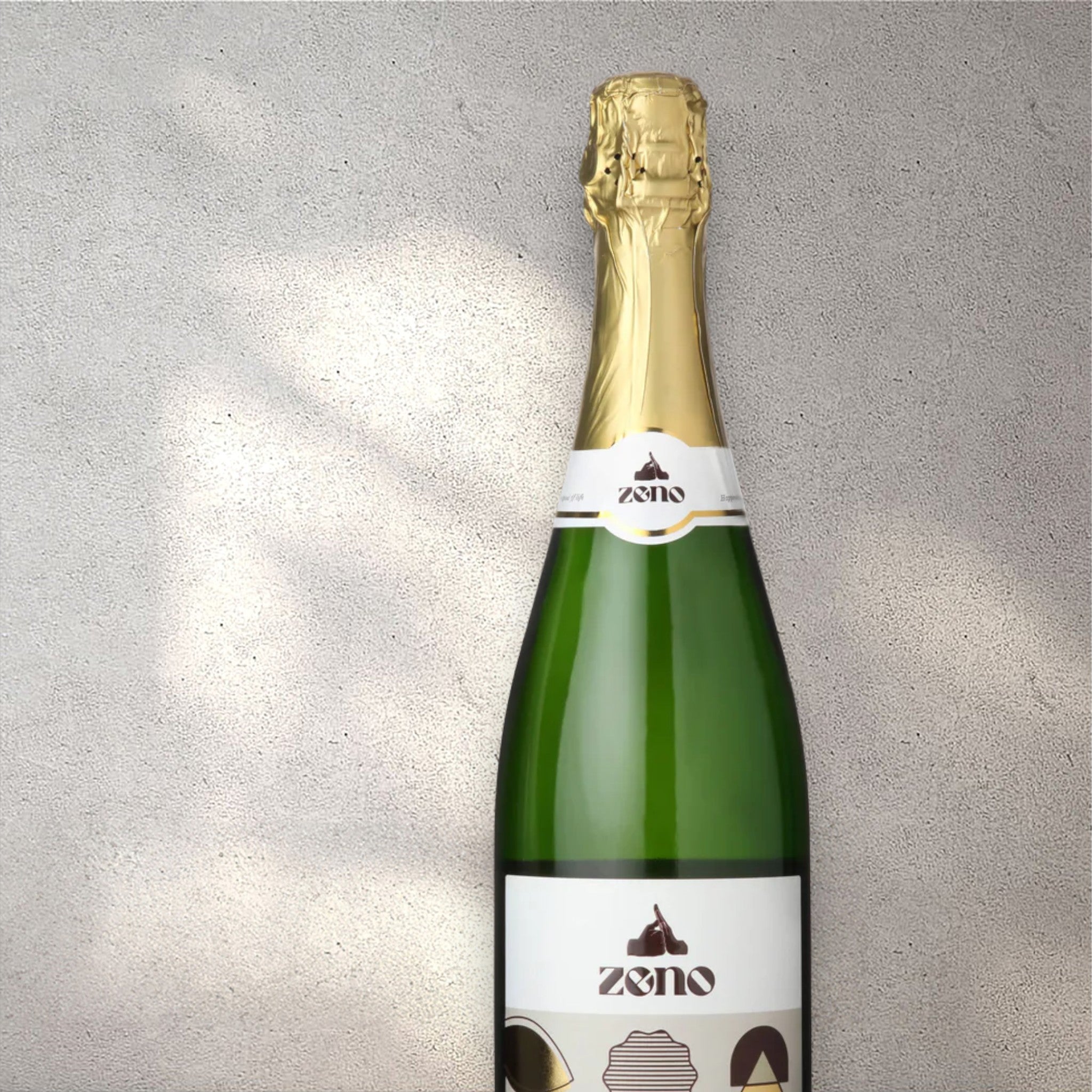 Closeup of a Zeno alcohol-free sparkling wine bottle with a detailed label, set against a textured concrete wall, highlighting its refined design and clear, sparkling color.
